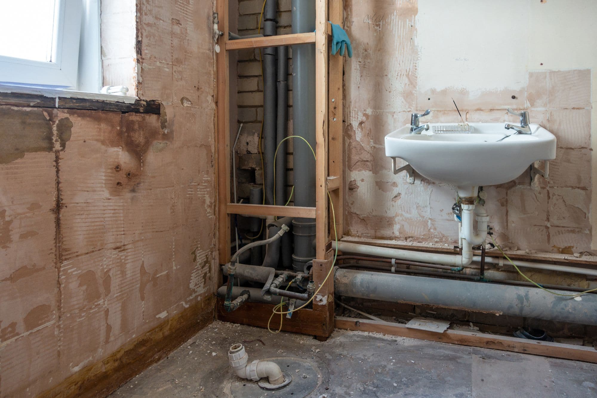 A bathroom stripped back to the walls with pipework exposed